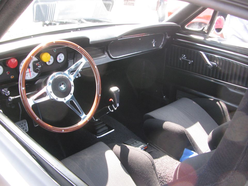 Car interior showing a wood-rimmed steering wheel, racing seats, and floor shifter