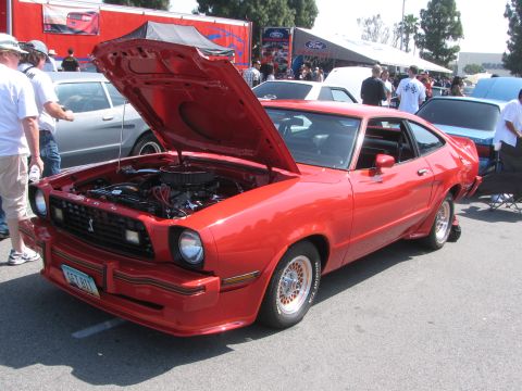 1996 Ford C-350 (Centurion Conversions) - Red 1975 Ford Mustang II coupe at an outdoor event, hood raised to reveal the engine bay.