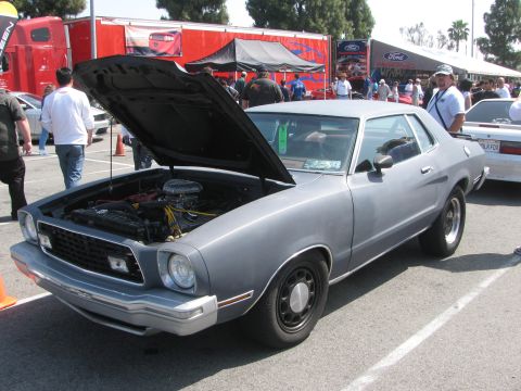 1996 Ford C-350 (Centurion Conversions) - A gray Ford Mustang II coupe is displayed with its hood open, revealing the engine bay.