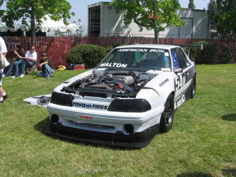 1996 Ford C-350 (Centurion Conversions) - White Ford Mustang race car with hood open, "AMERICAN IRON" and "WALTON" on windshield, "54" on door, parked on grass.