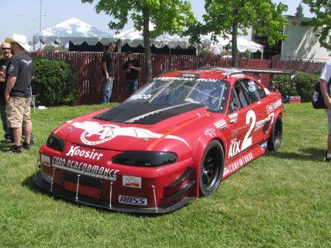 1996 Ford C-350 (Centurion Conversions) - A red race car with numerous sponsor decals and the number 2 prominently displayed is parked on grass.