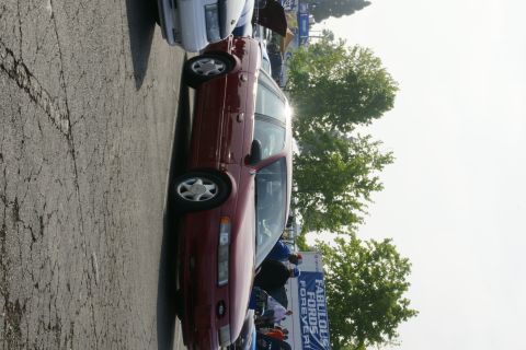 1992 Ford Taurus - A maroon station wagon is parked at an outdoor event with a banner in the background.