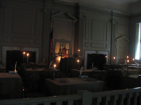 1996 Ford C-350 (Centurion Conversions) - A dimly lit room, likely Independence Hall, set up for a meeting with quill pens and candles on tables.