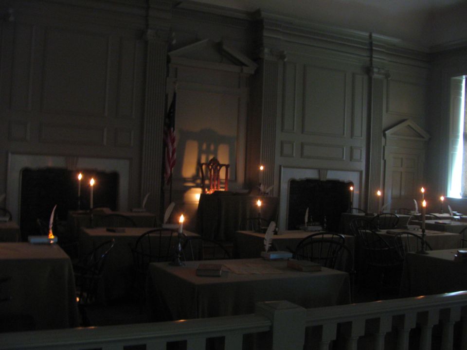 Assembly room with tables, chairs, and candles lit, an American flag visible