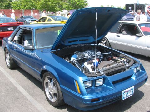 1996 Ford C-350 (Centurion Conversions) - Blue coupe with hood open, showing a modified engine. Other cars are visible in the background.