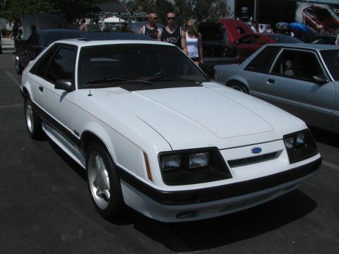 1996 Ford C-350 (Centurion Conversions) - A white coupe with black trim and a sunroof is parked at an outdoor event.