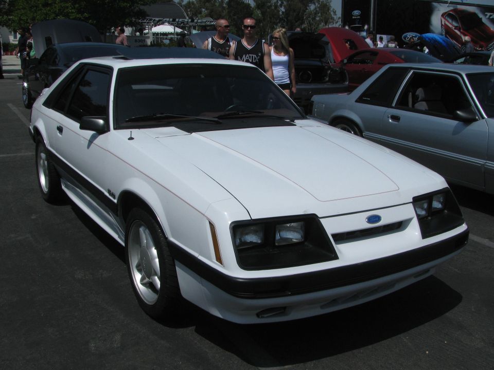 White coupe with black trim and sunroof, front quarter view