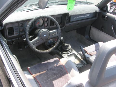 1996 Ford C-350 (Centurion Conversions) - The interior of a 1987 Ford Mustang GT convertible shows the dashboard, steering wheel, and manual shifter.