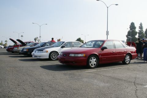 1992 Ford Taurus - A line of cars, including a red 1996 Ford Taurus, parked in an outdoor lot on a sunny day.