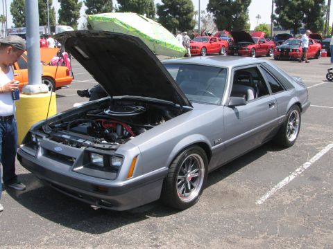 1996 Ford C-350 (Centurion Conversions) - A gray 1987 Ford Mustang GT is parked with its hood open at an outdoor car show.