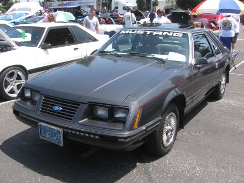1996 Ford C-350 (Centurion Conversions) - Gray Ford Mustang hatchback parked at an outdoor event, with other vehicles visible.