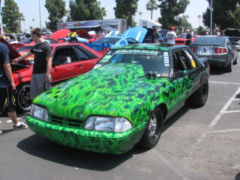 1996 Ford C-350 (Centurion Conversions) - Customized Ford Mustang with green flame paint and racing modifications at a car show.