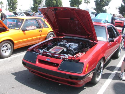 1996 Ford C-350 (Centurion Conversions) - Red coupe with hood open, revealing the engine bay. An orange coupe is parked nearby.