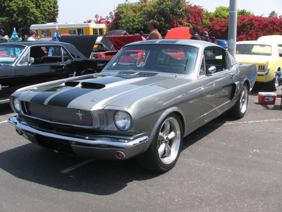 Gray 1965 Ford Mustang Fastback with black stripes, parked at a car show