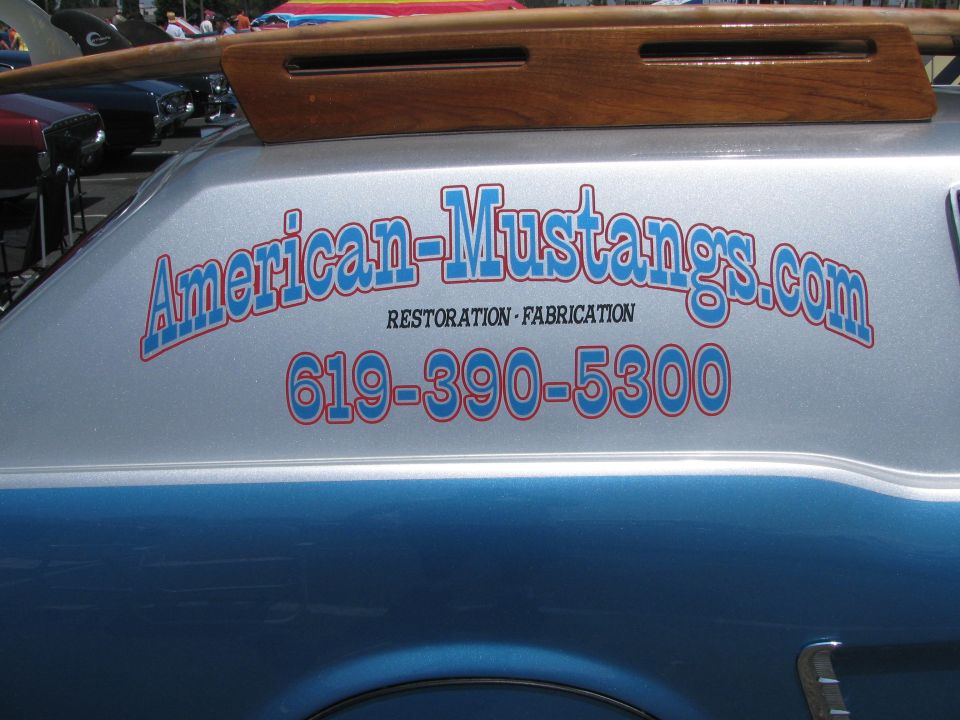 Silver and blue van side view with "American-Mustangs.com" text and phone number