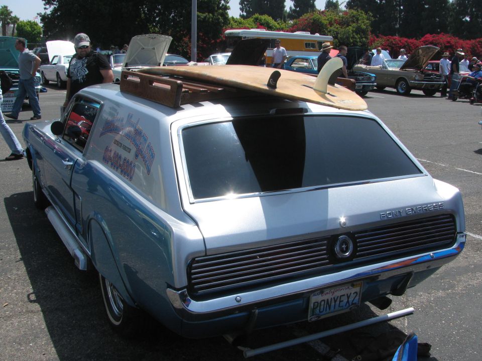 1967 Ford Mustang Station Wagon, light blue and silver, with surfboard on roof rack. Pony Express text on rear