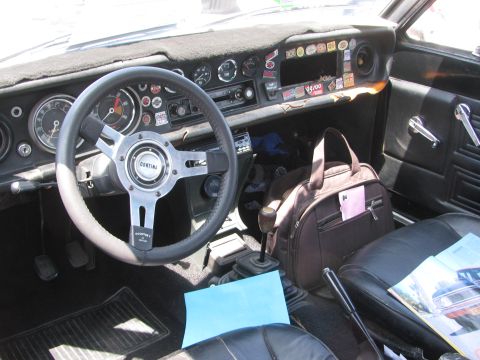 1996 Ford C-350 (Centurion Conversions) - Interior of a car with a Cortina steering wheel and a dashboard covered in stickers.