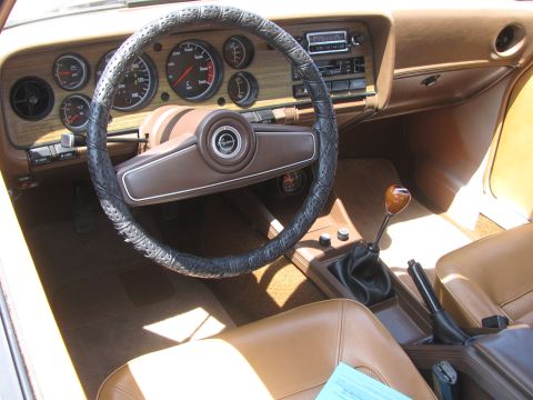 1996 Ford C-350 (Centurion Conversions) - The interior of a car features a brown dashboard with wood grain accents and a leather-wrapped steering wheel.