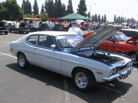 1996 Ford C-350 (Centurion Conversions) - A white and blue coupe, identified as a Capri, is displayed with its hood open at an outdoor car show.