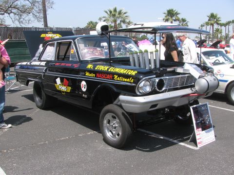 1996 Ford C-350 (Centurion Conversions) - A modified black Ford sedan with racing decals and a prominent exhaust system is displayed outdoors.
