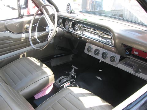1996 Ford C-350 (Centurion Conversions) - The interior of a classic vehicle features tan upholstery, a prominent steering wheel, and a set of four auxiliary gauges mounted below the…