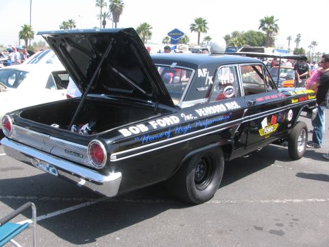 1996 Ford C-350 (Centurion Conversions) - A black Ford Fairlane drag car is parked with its trunk open, displaying racing decals and text on its side.