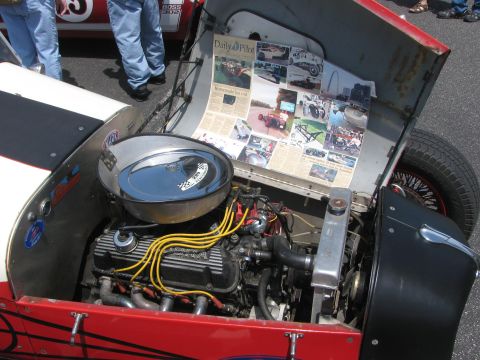 1996 Ford C-350 (Centurion Conversions) - The hood of a hot rod is open, revealing the engine and a display of newspaper clippings and photos.