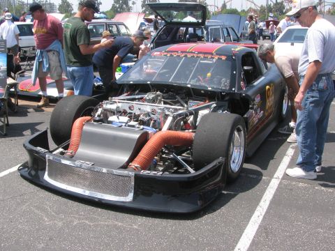 1996 Ford C-350 (Centurion Conversions) - A custom-built race car with its engine exposed is on display, drawing the attention of onlookers.