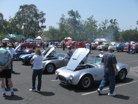 1996 Ford C-350 (Centurion Conversions) - Attendees examine classic cars with their hoods open at an outdoor car show on a sunny day.