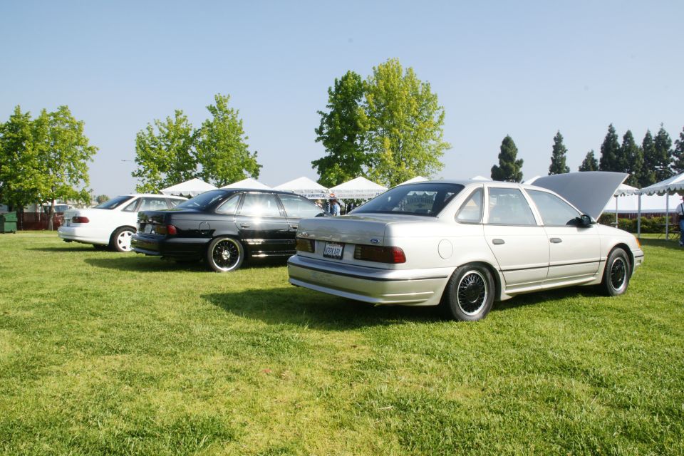 Silver 1992 Ford Taurus parked on grass with hood up, other cars behind it