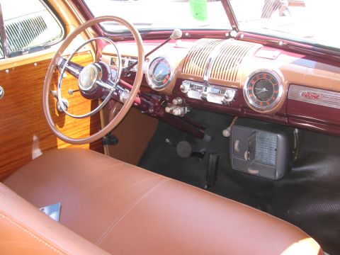 1996 Ford C-350 (Centurion Conversions) - The dashboard of a classic car features a prominent steering wheel, wood trim, and a central radio unit.
