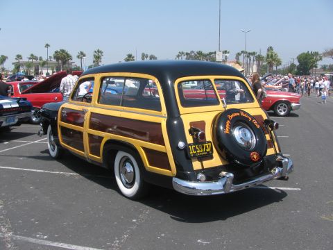 1996 Ford C-350 (Centurion Conversions) - A classic woodie station wagon is parked in a lot with other vehicles and people.