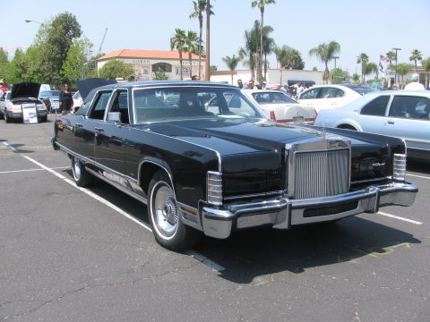 1996 Ford C-350 (Centurion Conversions) - A classic black Lincoln Continental Mark V is parked in a lot with other vehicles under a sunny sky.