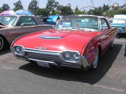 1996 Ford C-350 (Centurion Conversions) - A red 1962 Ford Thunderbird is parked outdoors, with other vehicles and trees in the background.