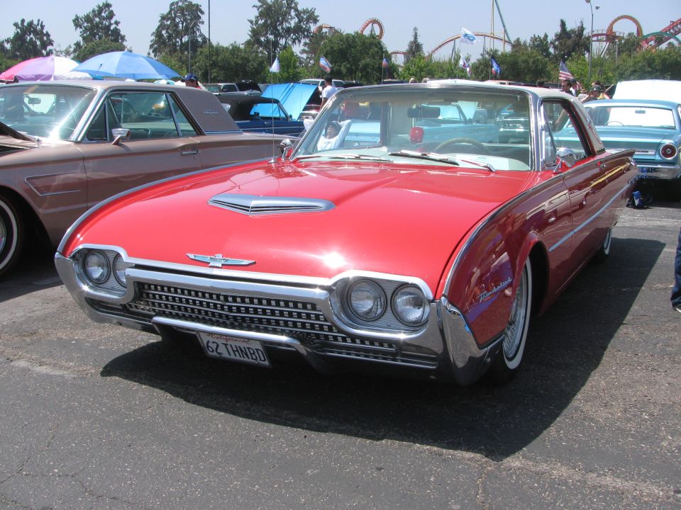 Red 1962 Ford Thunderbird coupe with a chrome grille and hood scoop. License plate reads '62 THNBD'
