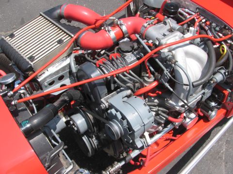 1996 Ford C-350 (Centurion Conversions) - Close-up view of a modified engine bay with prominent red hoses and various engine parts.