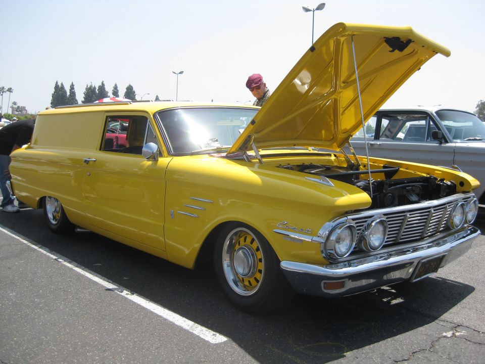 Yellow 1961 Mercury Econoline panel van, hood open, showing engine. Three vents on fender