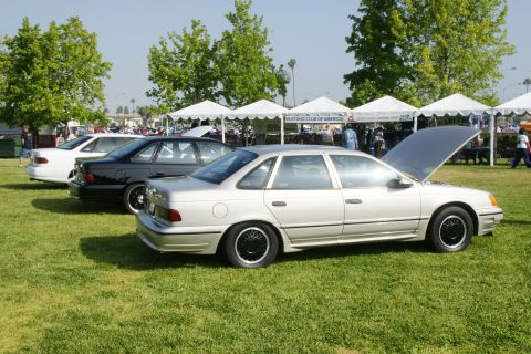 1992 Ford Taurus - Several Ford Taurus sedans are displayed on a grassy field under tents at an outdoor car show.