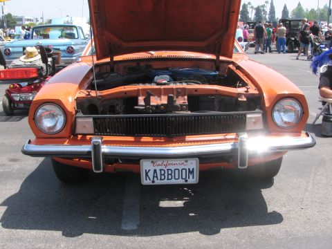 1996 Ford C-350 (Centurion Conversions) - Front view of an orange car with its hood open, parked outdoors at an event.