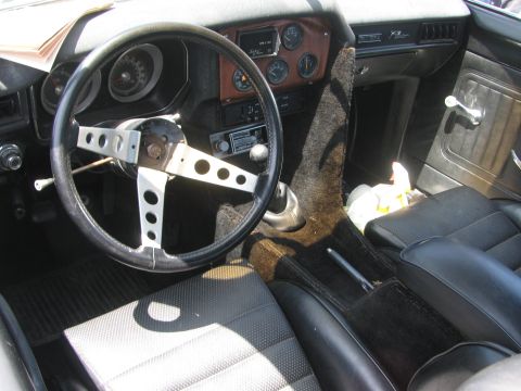 1996 Ford C-350 (Centurion Conversions) - The interior of the vehicle shows an aftermarket steering wheel and a woodgrain dashboard with multiple gauges.