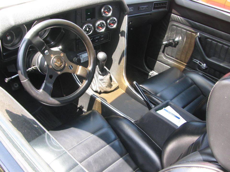 Interior shot of a custom van with black leather seats, a three-spoke steering wheel, and multiple gauges on the dashboard