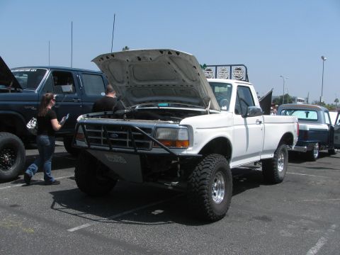 1996 Ford C-350 (Centurion Conversions) - White 1996 Ford C-350 (Centurion Conversions) pickup truck with its hood open at an outdoor event.