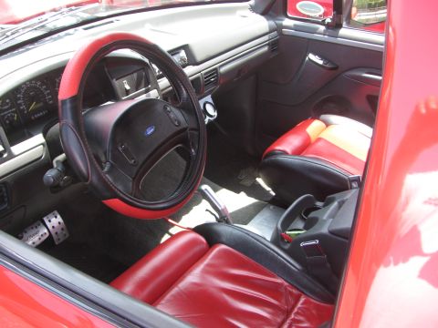 1996 Ford C-350 (Centurion Conversions) - The interior of a red truck features a custom steering wheel and multi-colored seats.