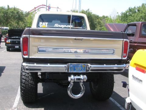 1996 Ford C-350 (Centurion Conversions) - Rear view of a lifted Ford F-Series pickup truck with a chrome bumper and tow hitch. Another vehicle is partially visible to the right.