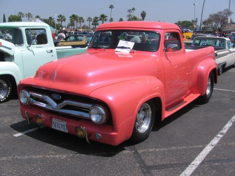 1996 Ford C-350 (Centurion Conversions) - This custom 1956 Ford F-100 pickup truck features a vibrant pink paint job with subtle flame graphics and polished alloy wheels.