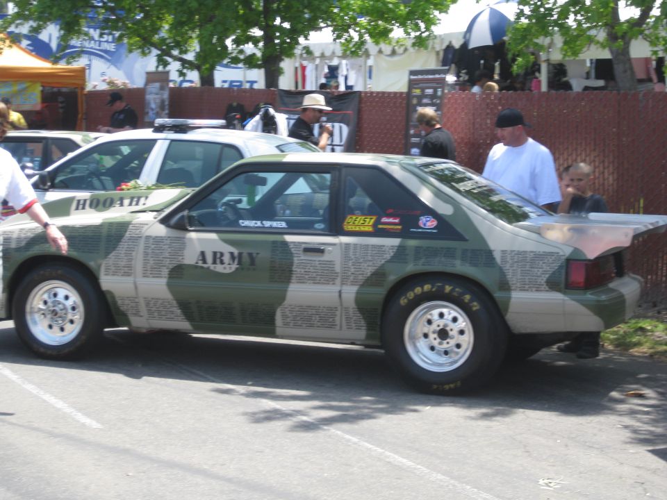Side view of a car with camouflage and newspaper print wrap, "ARMY" text