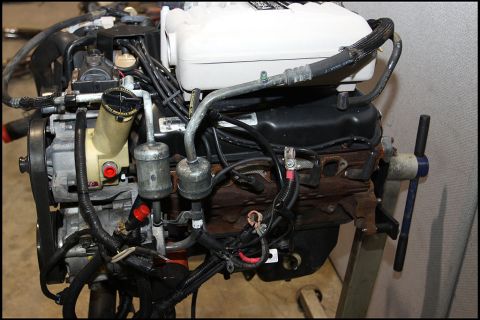 1994 Ford Bronco - Engine assembly on a stand, various hoses, wiring, and engine components.