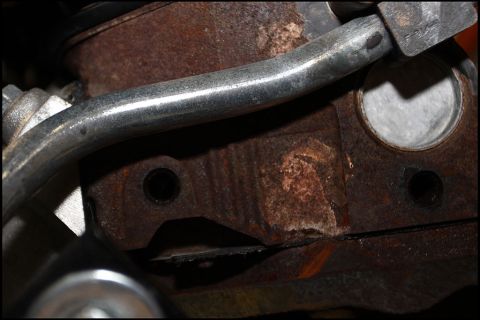 1994 Ford Bronco - This is a close-up view of a heavily rusted engine component with a metal pipe.