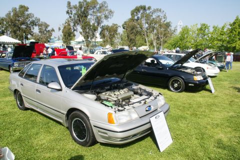 1992 Ford Taurus - A silver 1992 Ford Taurus is displayed with its hood open at an outdoor car show, alongside other vehicles.