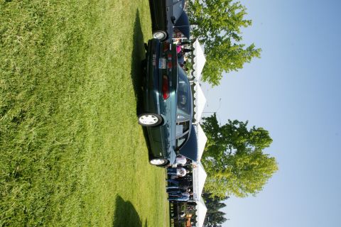 1992 Ford Taurus - A green sedan is displayed at an outdoor event with tents and other vehicles present.